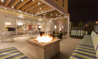 a patio with a fire pit surrounded by couches and chairs , creating a cozy atmosphere at Home2 Suites by Hilton Canton