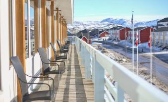 a row of chairs is set up on a balcony with a view of snow - covered mountains at Hotel Hvide Falk