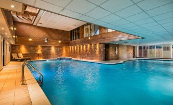 a large indoor swimming pool with a wooden ceiling and walls , surrounded by blue water at Macdonald Elmers Court Hotel