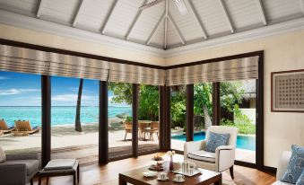 a modern living room with large windows offering a view of the ocean and a dining table at Taj Exotica Resort & Spa
