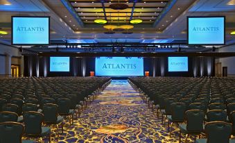 a large , well - lit conference room with rows of chairs arranged in front of a stage at The Royal at Atlantis
