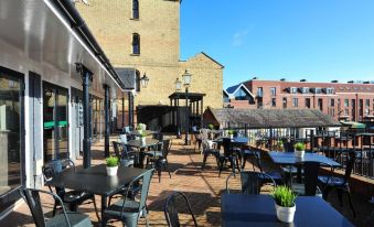 an outdoor dining area with tables and chairs , surrounded by a brick building and a clear blue sky at The White Hart