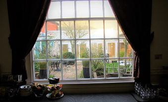 a window with a view of an outdoor area , including tables and chairs , and a teapot on the windowsill at Canterbury Hotel