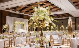 a large white and gold centerpiece with flowers is set up in a room , surrounded by tables and chairs at Raleigh Marriott Crabtree Valley