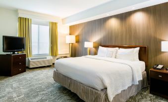 a hotel room with a large bed in the center of the room , surrounded by various pieces of furniture at SpringHill Suites Florence