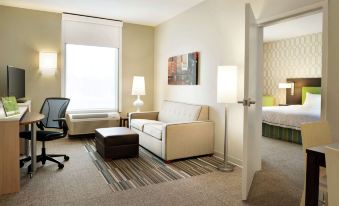 a small living room with a couch , a chair , a tv , and a dining table at Home2 Suites by Hilton Milwaukee Brookfield