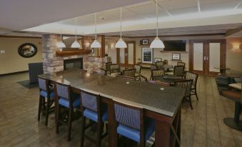 a large dining room with multiple tables and chairs , a fireplace , and pendant lights hanging from the ceiling at Hampton Inn Billings