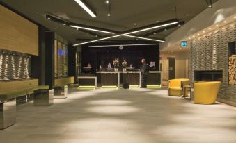 a modern , well - lit lobby with multiple reception desks and seating areas , under a black ceiling with lights at Radisson Blu Waterfront Hotel, Stockholm