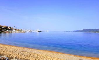 a serene beach scene with a clear blue sky , calm water , and a distant view of buildings in the distance at Mare E Monti