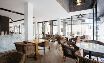 a modern restaurant with wooden tables and chairs , large windows , and pendant lights , providing a pleasant atmosphere for dining at Diamond Park Inn Chiangrai & Resort