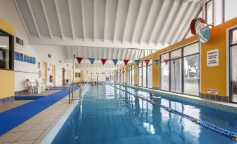 an indoor swimming pool with a long blue lane and red and white flags hanging from the ceiling at Quest Sanctuary Lakes