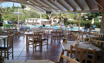 an outdoor dining area with tables and chairs arranged around a pool , providing a pleasant atmosphere for guests at Anita