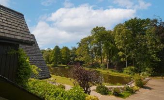 a park with a pond surrounded by trees and a stone sculpture , under a partly cloudy sky at Willowbeck Lodge Boutique Hotel