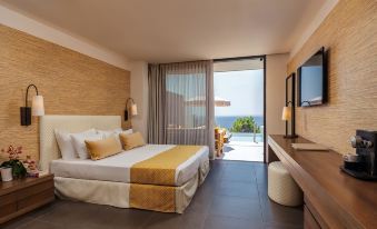 a hotel room with a king - sized bed , a flat - screen tv , and a balcony overlooking the ocean at White Rocks Hotel Kefalonia