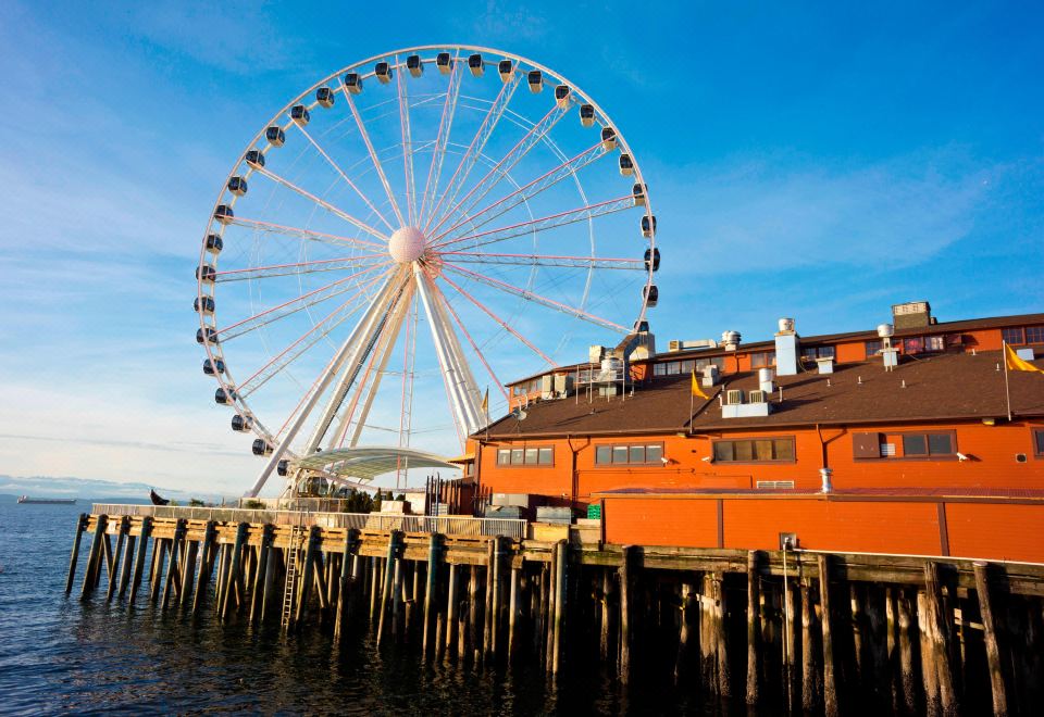 a large ferris wheel is seen in the background , with a building and dock visible in the foreground at Courtyard Seattle North/Lynnwood Everett