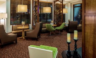 a modern lounge area with green and brown chairs , tables , and large windows , creating a warm and inviting atmosphere at Hilton Garden Inn Uniontown