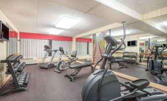 a well - equipped gym with various exercise equipment , including treadmills and stationary bikes , arranged in a spacious room at Ramada by Wyndham Cumberland Downtown