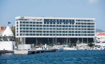 a large white hotel building surrounded by water , with several boats docked in the harbor at Octant Ponta Delgada