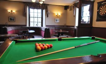 a billiards table with a red ball and two pool sticks in the corner of a room at The Punchbowl Hotel