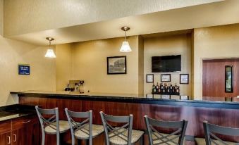 a modern bar with wooden cabinets , black marble countertops , and multiple wine bottles on display at Cobblestone Hotel & Suites - Erie