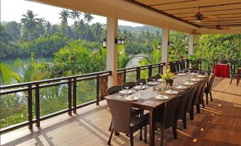 a long dining table set up for a meal , with chairs arranged around it , overlooking a beautiful view of the countryside at Loboc River Resort