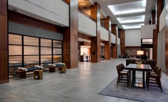 a large , modern hotel lobby with multiple seating areas and a dining table in the center at Winston-Salem Marriott