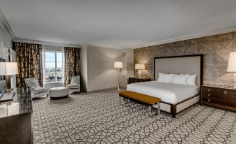 a large , well - lit hotel room with a bed , couch , chair , and other furniture arranged in a stylish and elegant manner at Hilton Columbus at Easton