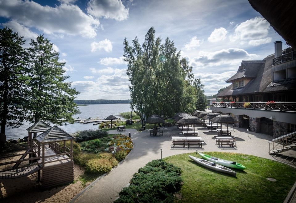 a serene outdoor setting with a lake , grassy area , and trees , as well as some tables and chairs for outdoor dining at Porto Resort