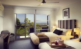 a hotel room with two beds and a view of the mountains through the sliding glass doors at Mercure Clear Mountain Lodge