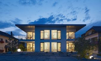 a modern house with a large window and two balconies is shown at dusk , lit up by lights at Lumina Apartments