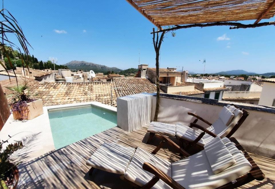 The Chateau de has a patio with chairs and an umbrella on top of the deck, which overlooks the pool at Petit Hotel Forn NOU