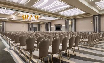 a conference room with rows of chairs arranged in a semicircle , and a podium at the front of the room at Ramada by Wyndham Ramnicu Valcea