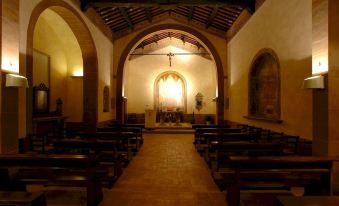 a dimly lit church with wooden pews and an arched doorway , possibly indicating an altar at Abbadia Sicille Relais