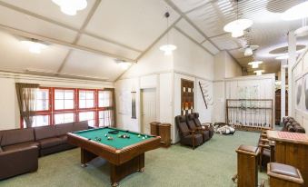 a large , well - lit room with a pool table , couches , and chairs arranged in the center at Ranua Resort Holiday Villas