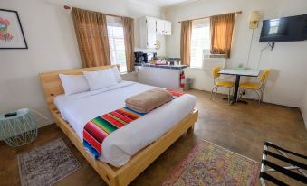a cozy bedroom with a wooden bed , white sheets , and a colorful striped blanket on the bed at Antelope Lodge