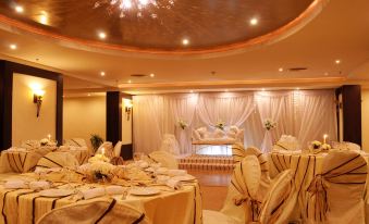 a large banquet hall is decorated with white tablecloths and chairs , creating a festive atmosphere at Aracan Pyramids Hotel