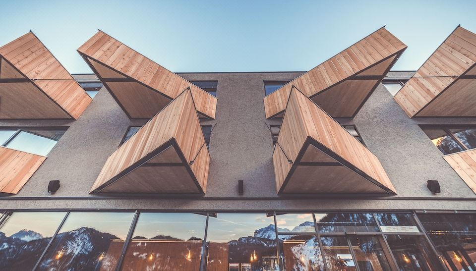a modern building with wooden triangular roofs and large windows , situated in a city setting at Spaces Hotel