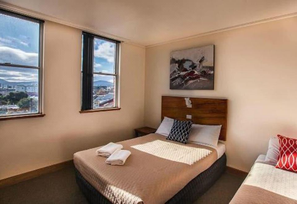 a bed with a brown blanket and white pillows is in a room with a window at Prince of Wales Hotel