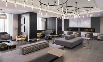 a modern lounge area with gray couches , chairs , and a large chandelier hanging from the ceiling at Residence Inn Halifax Dartmouth