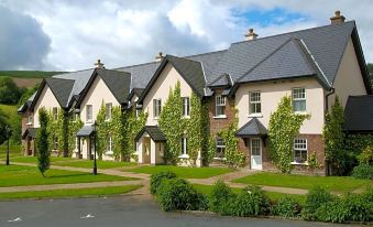 a row of houses with ivy - covered roofs and balconies , surrounded by a grassy area and trees at BrookLodge & Macreddin Village