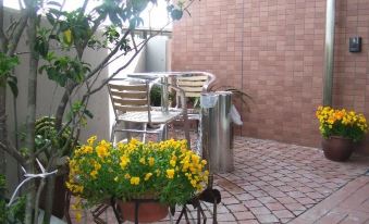 a brick patio with a dining table and chairs , potted plants , and yellow flowers in a pot at Toyota Village