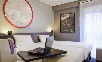 a hotel room with a bed , a laptop on a table , and a painting on the wall at Ibis Styles Paris Mairie de Montreuil