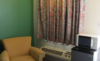 a cozy living room with a yellow chair , a microwave , and a television mounted on the wall at Village Inn