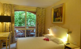 a hotel room with a king - sized bed , a tv , and a window overlooking a garden at Hotel Napoleon