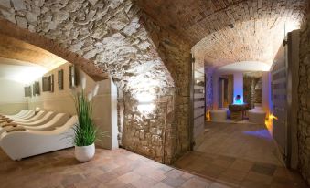 a stone building with a living room area and a staircase leading to an upper level at Palazzo Leopoldo Dimora Storica & Spa