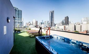 a rooftop with a hot tub and a view of the city , including a tall building in the background at Space Hotel