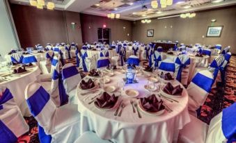 a large banquet hall with tables set up for a formal event , featuring white tablecloths , blue napkins , and purple centerpieces at Holiday Inn Richmond