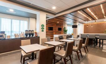 a modern dining area with wooden tables and chairs , a coffee maker , and a tv mounted on the wall at Wingate by Wyndham Angola