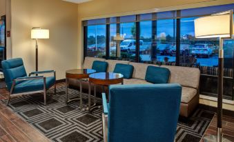 a room with a couch , two chairs , and a dining table in front of a large window at TownePlace Suites Detroit Belleville