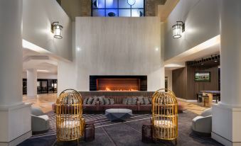 a modern living room with a large fireplace , comfortable seating arrangements , and two yellow birdcages on either side of the fireplace at Hilton Lexington/Downtown